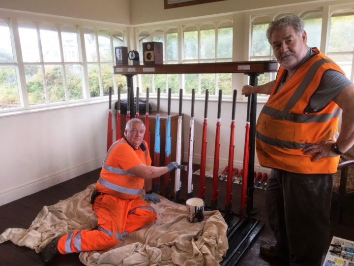 22/9/2022: Under the watchful eye of Roy Thompson, David Orr gives the lever frame a fresh coat of paint following changes to the signalling system. (R. Morton)